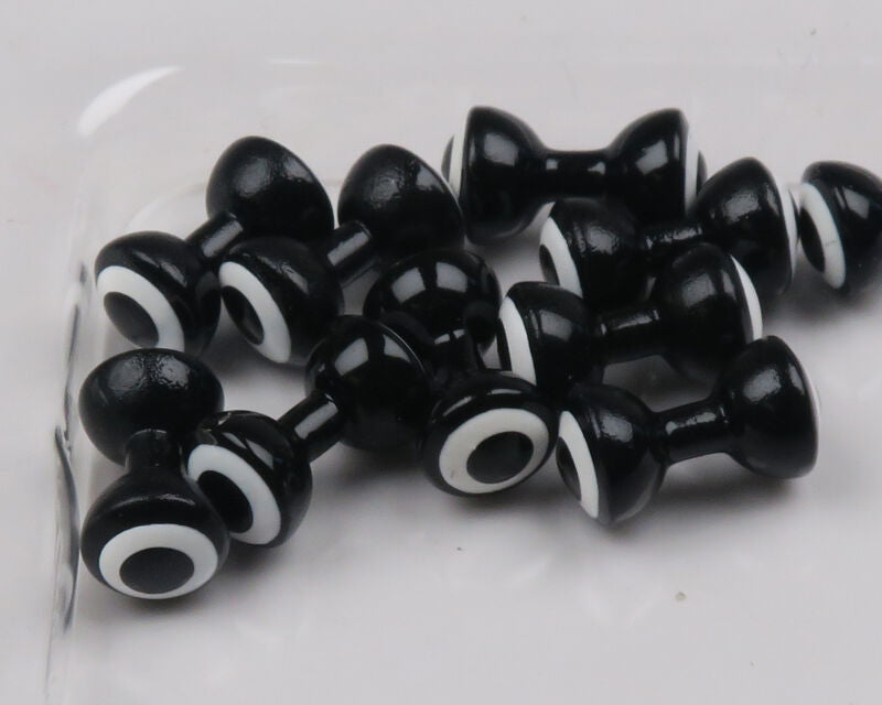 Glossy black double-pupil brass eyes with white concentric rings, dumbbell-shaped for fly tying
