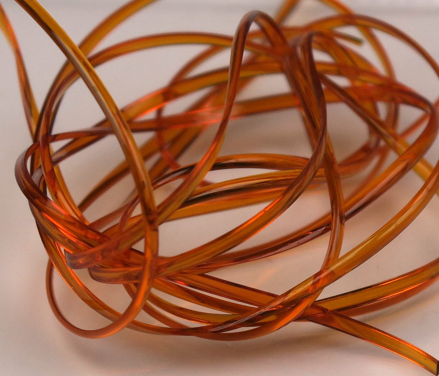 Translucent amber half-round D-rib coil, glossy plastic ribbing for fly tying