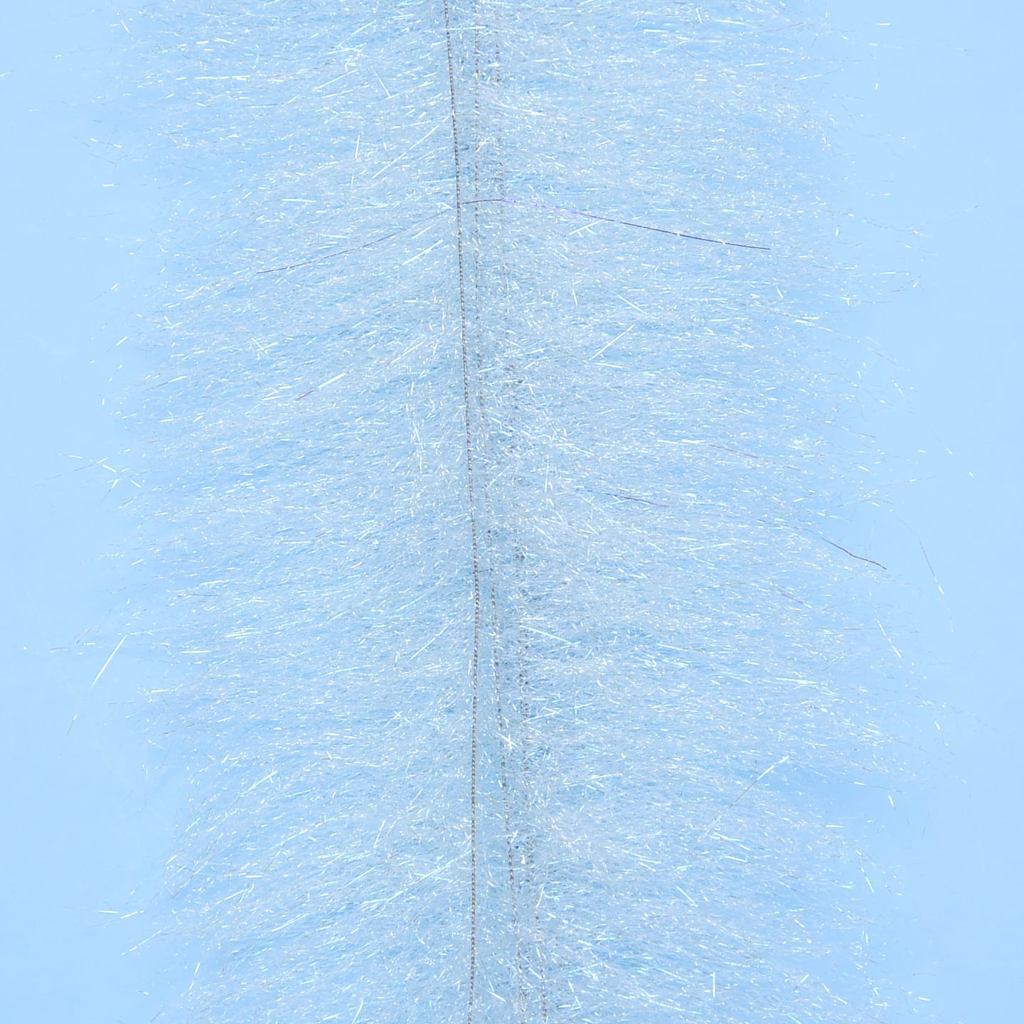 Pale blue fly tying brush with dense iridescent synthetic fibers and a visible stitched center
