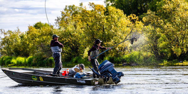 Three anglers fishing from a black Lowe boat with Yamaha motor on a river surrounded by green trees
