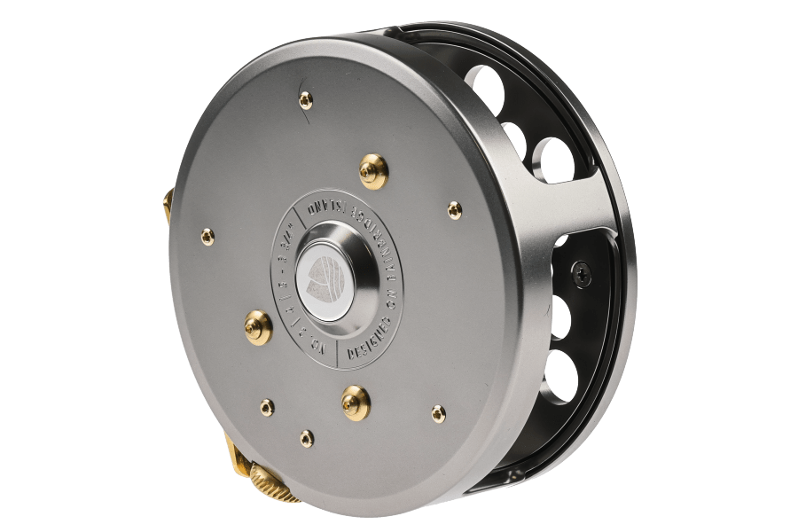 Silver-gray fly reel with brass-accented drag knobs, large ventilation cutouts, and a machined spool, shown from an angled