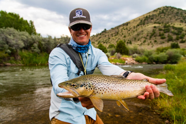 Fly fisherman holding brown trout catch at Silver Bow Club on mountain river in Montana