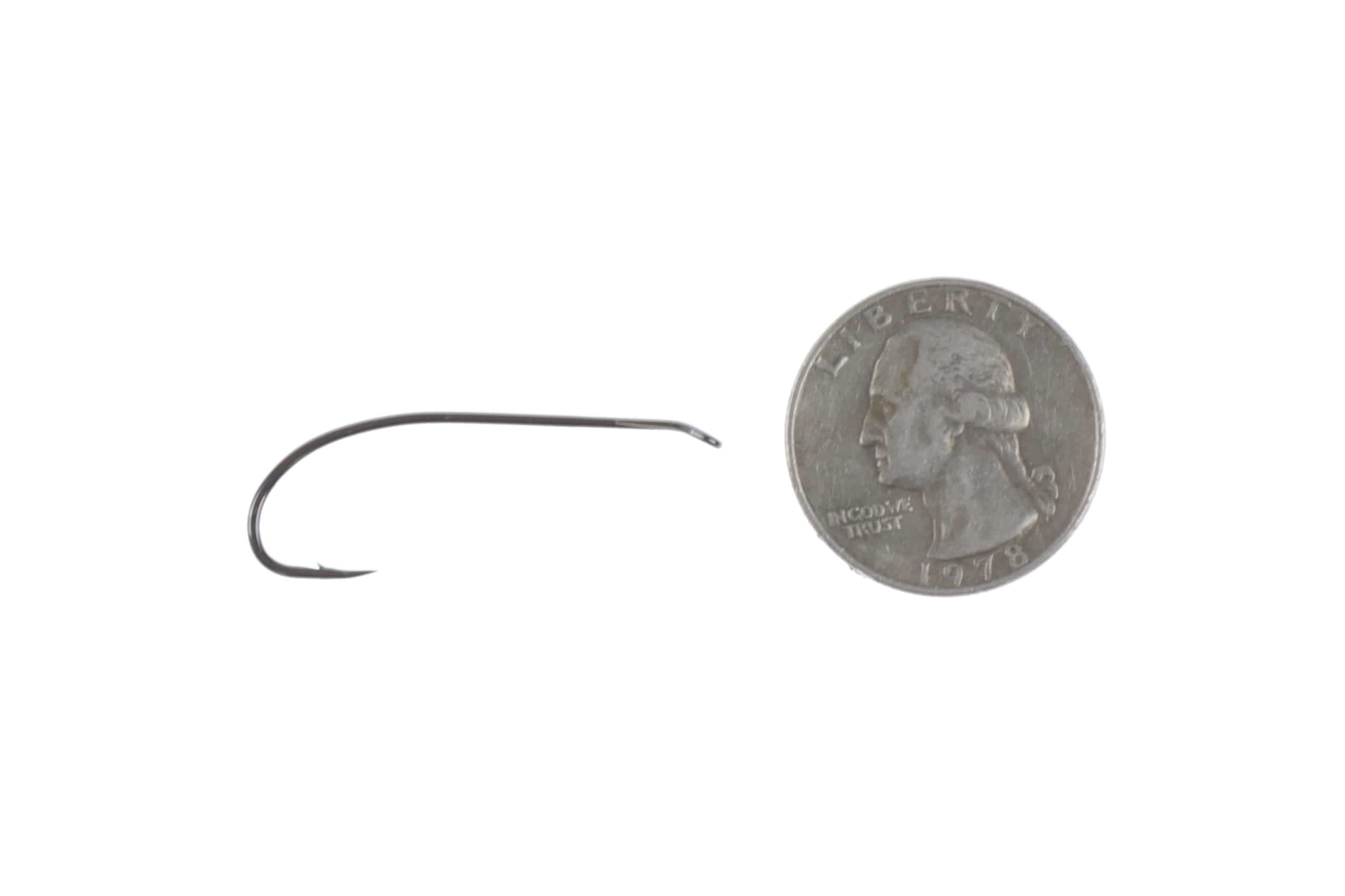 Gunmetal Ahrex Bomber fly tying hook, curved barbed metal piece displayed beside a US quarter for scale