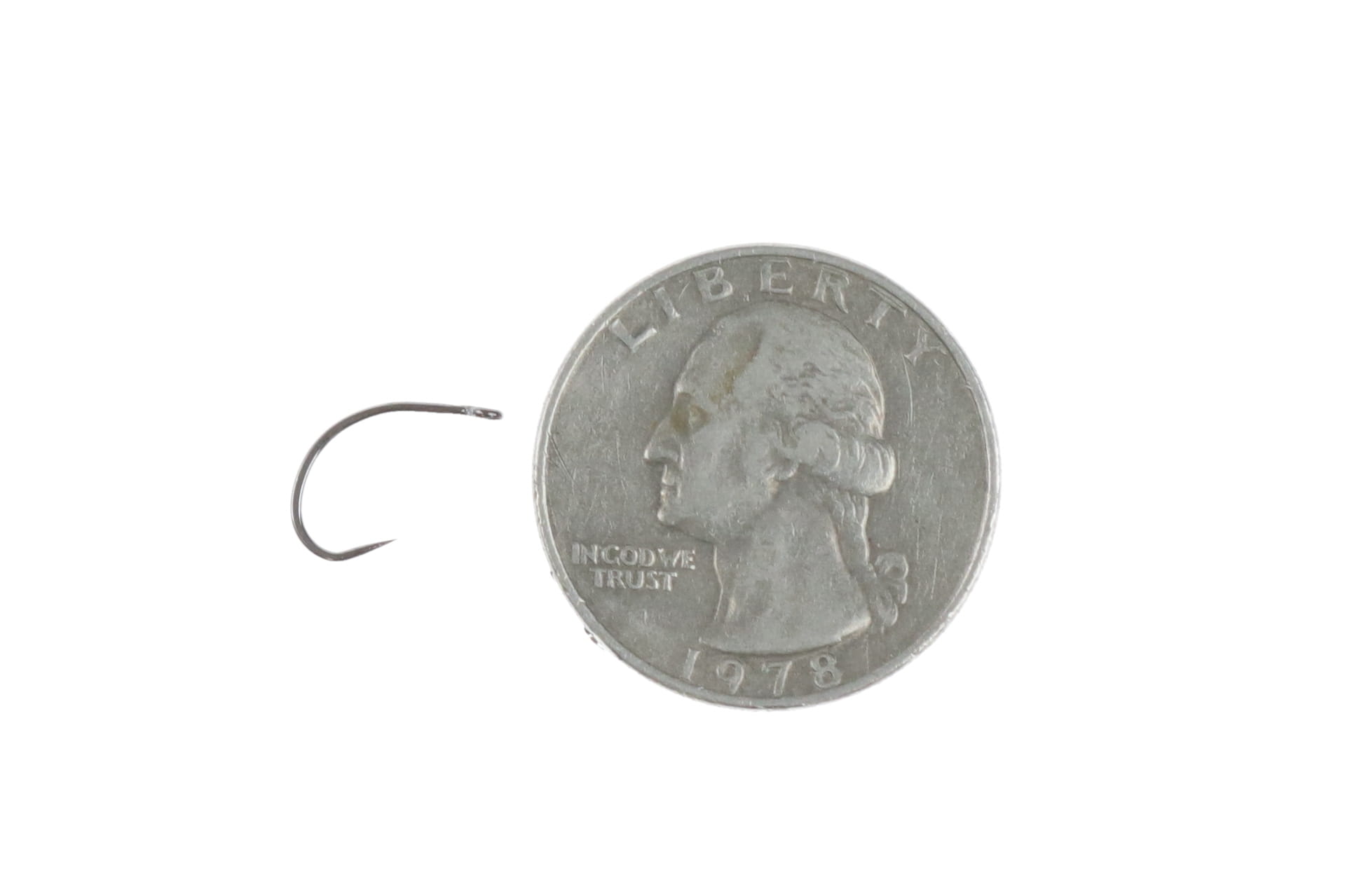 Small dark metallic curved barbless fly tying hook beside US quarter for scale