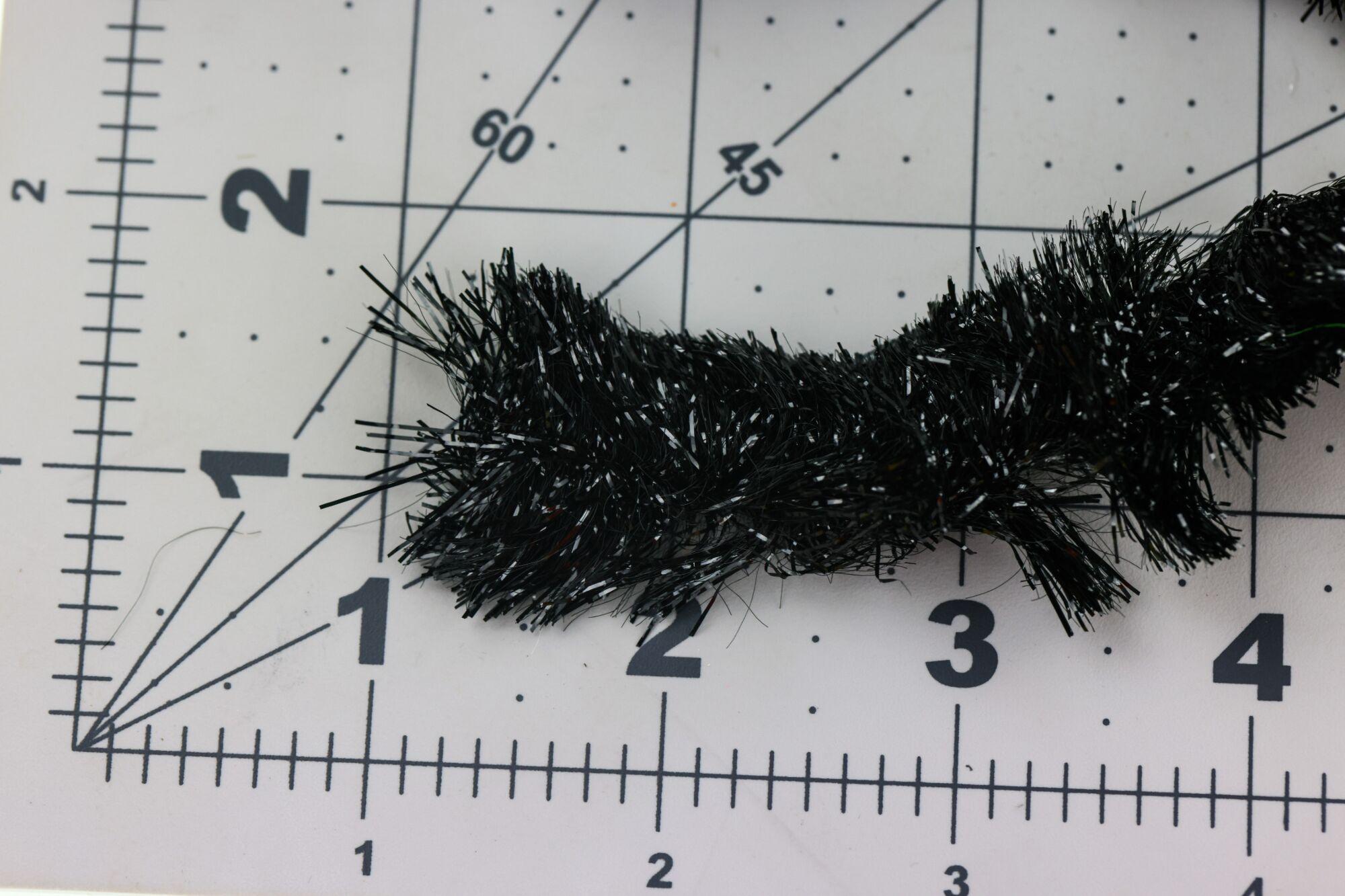 Black Gamechanger chenille with silver tinsel strands, dense fuzzy fly tying material on measurement grid