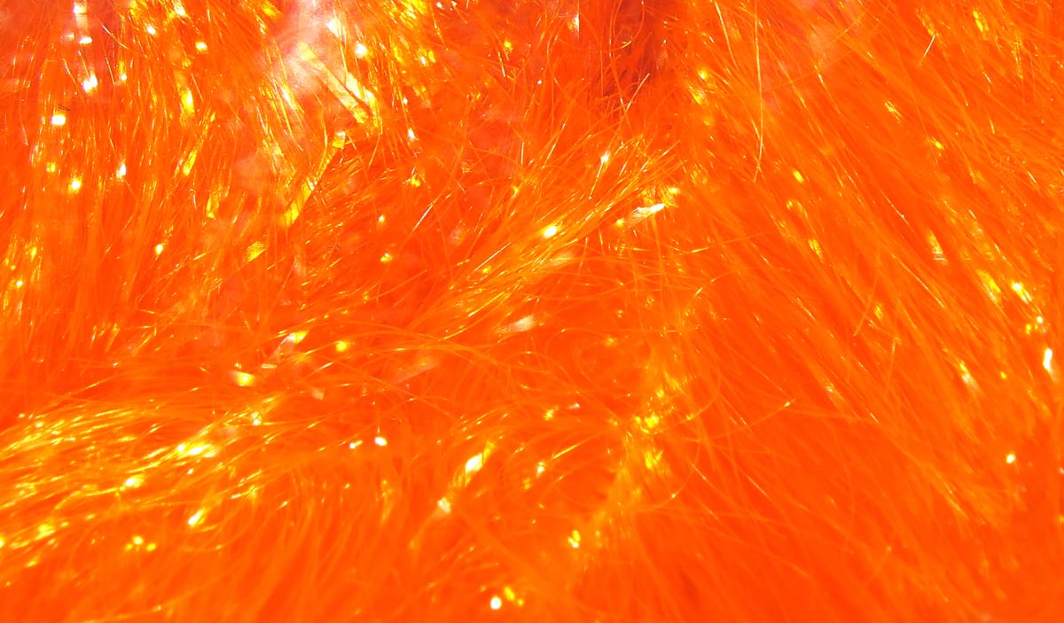 Bright fluorescent orange iridescent chenille fibers with fine sparkly strands for fly tying, plush textured material