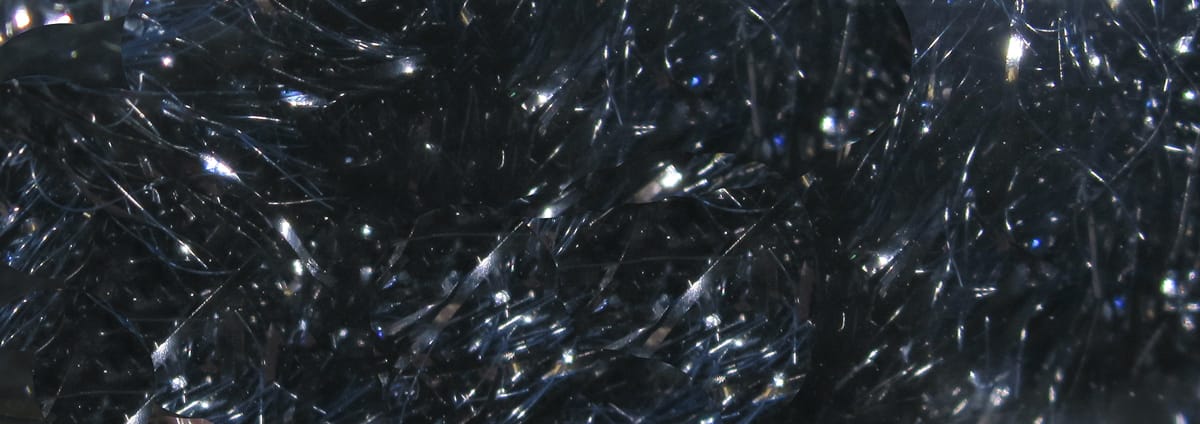 Dark iridescent black-blue chenille with reflective metallic flash fibers, fuzzy textured fly tying material