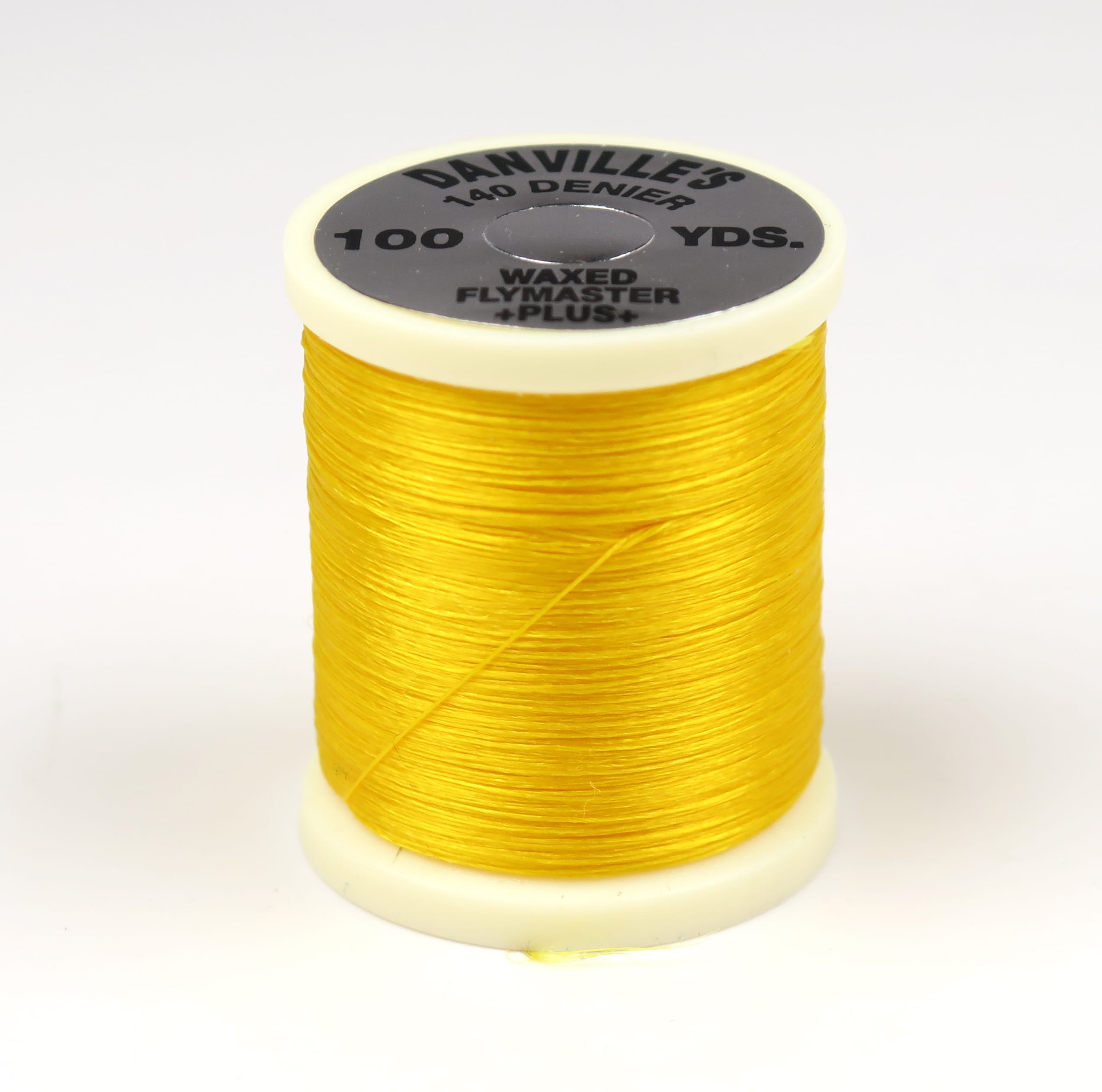 Bright yellow waxed 140 denier Danville Flymaster Plus thread on an off-white plastic spool for fly tying