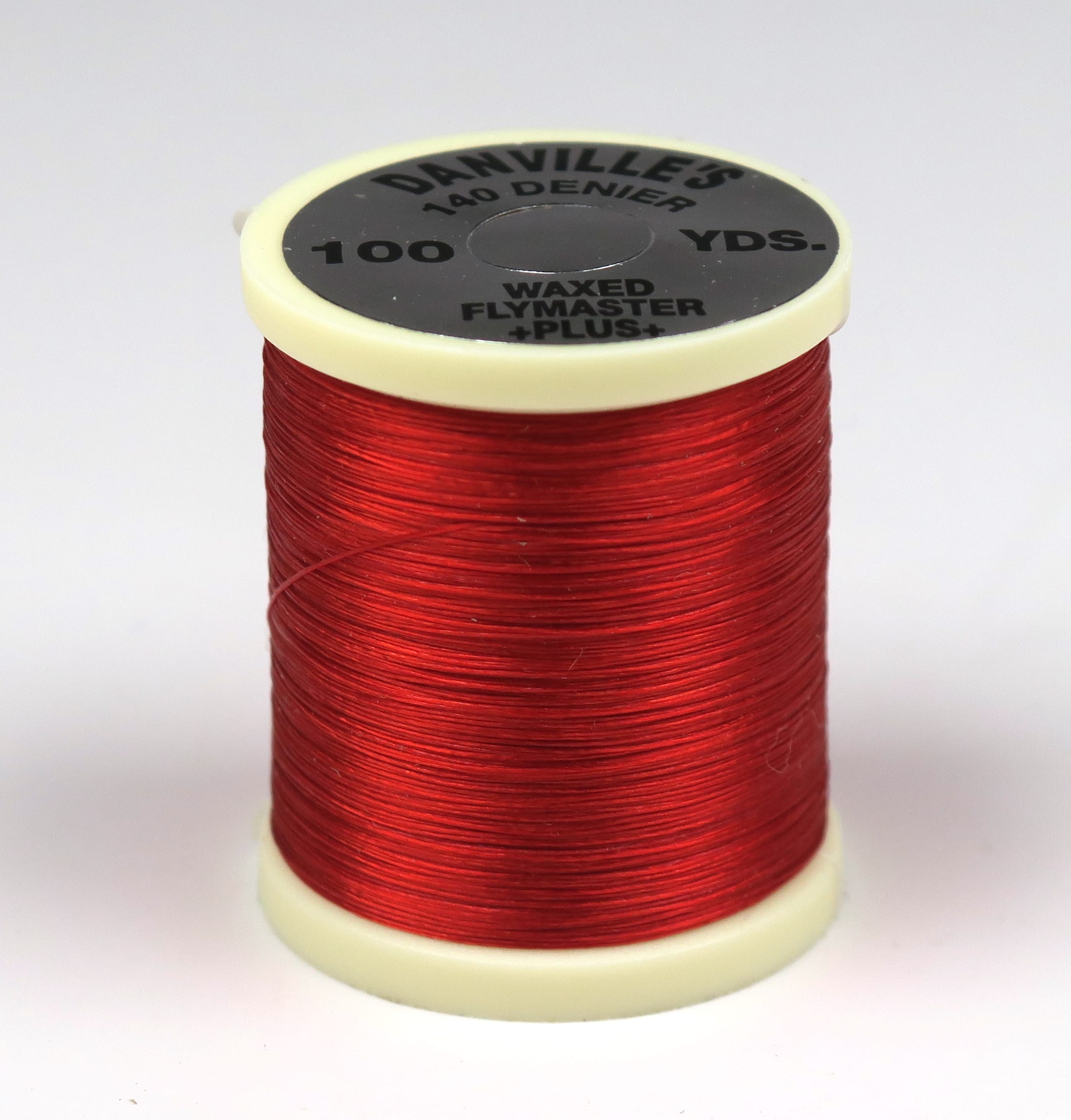 Red waxed 140 denier fly tying thread spool with cream plastic ends and black Danville label