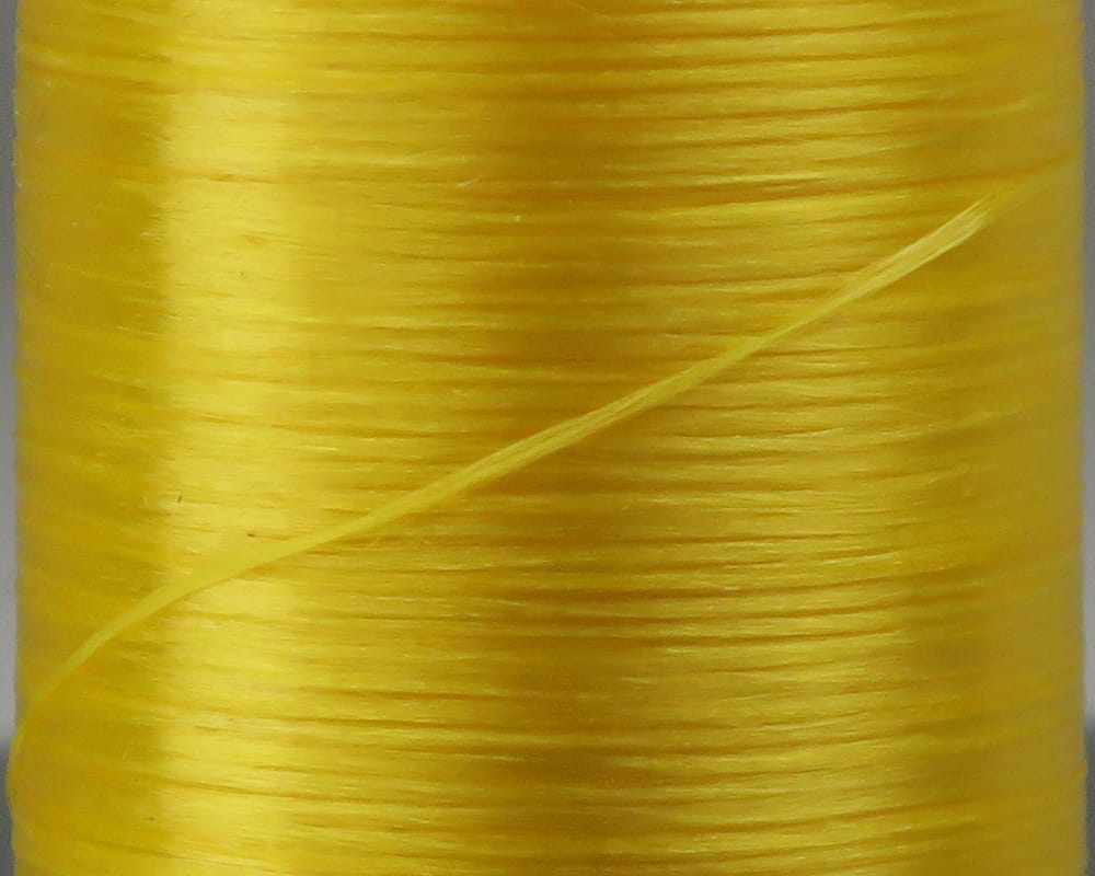 Bright yellow flat waxed nylon thread on spool, smooth glossy fibers, Danville 210 denier, ideal for fly tying