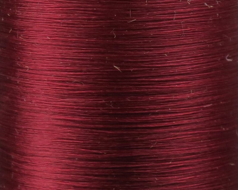 Burgundy Danville Flymaster 6/0 nylon fly tying thread spool close-up showing smooth glossy wound texture