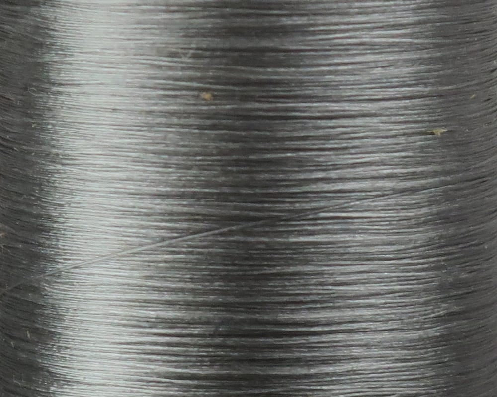 Close-up of Danville Flymaster 6/0 fly tying thread spool, smooth glossy silver-gray nylon, tightly wound fine denier thread