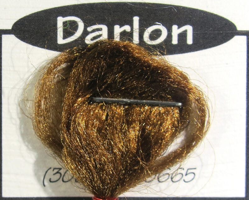Golden brown Darlon synthetic dubbing bundle secured with a black pin on white card, fly tying material