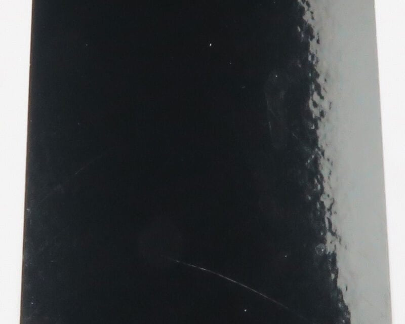 Black glossy D's Flyes Fino Skin sheet for fly tying, smooth reflective surface with textured right edge and faint scratches