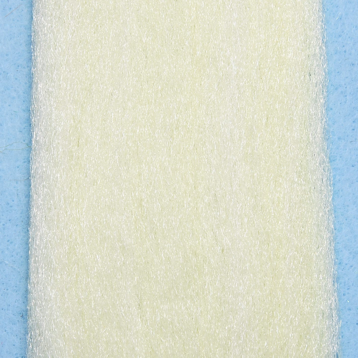 Cream off-white synthetic 3D fibers sheet with fine reflective strands on pale blue background for fly tying