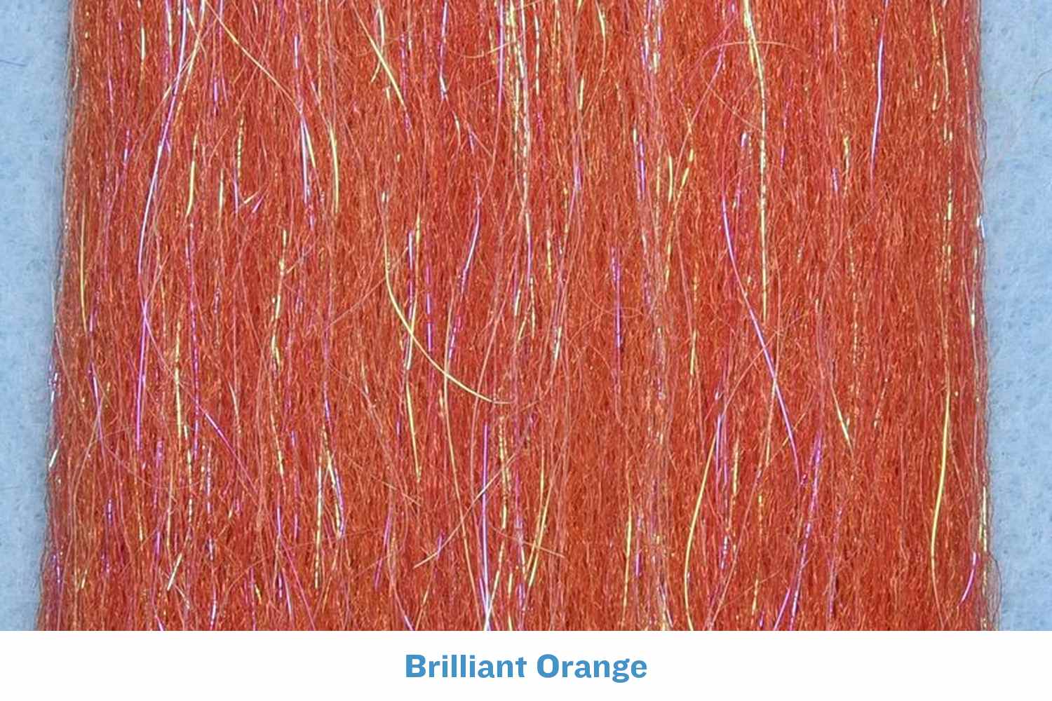 Brilliant orange synthetic fly tying fibers with iridescent pink-gold flash strands, fine textured hairlike material