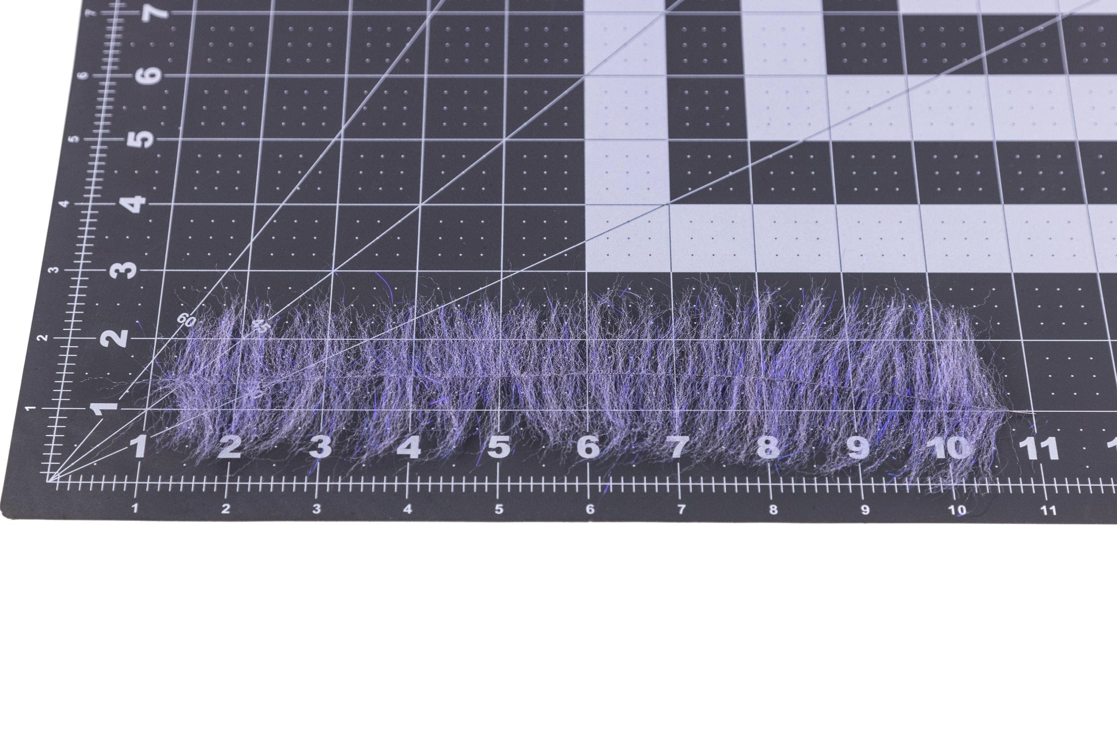Enrico Puglisi Anadromus purple synthetic brush fibers for fly tying laid across black grid cutting mat with ruler