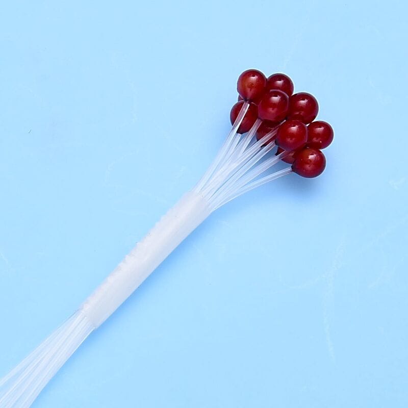 Bundle of glossy red crab and shrimp fly-tying eyes on clear flexible stems against pale blue background