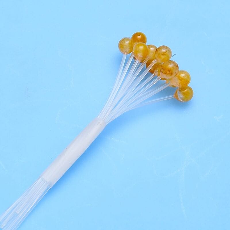 Amber translucent crab and shrimp eyes on clear plastic stems bundled on white base for fly tying