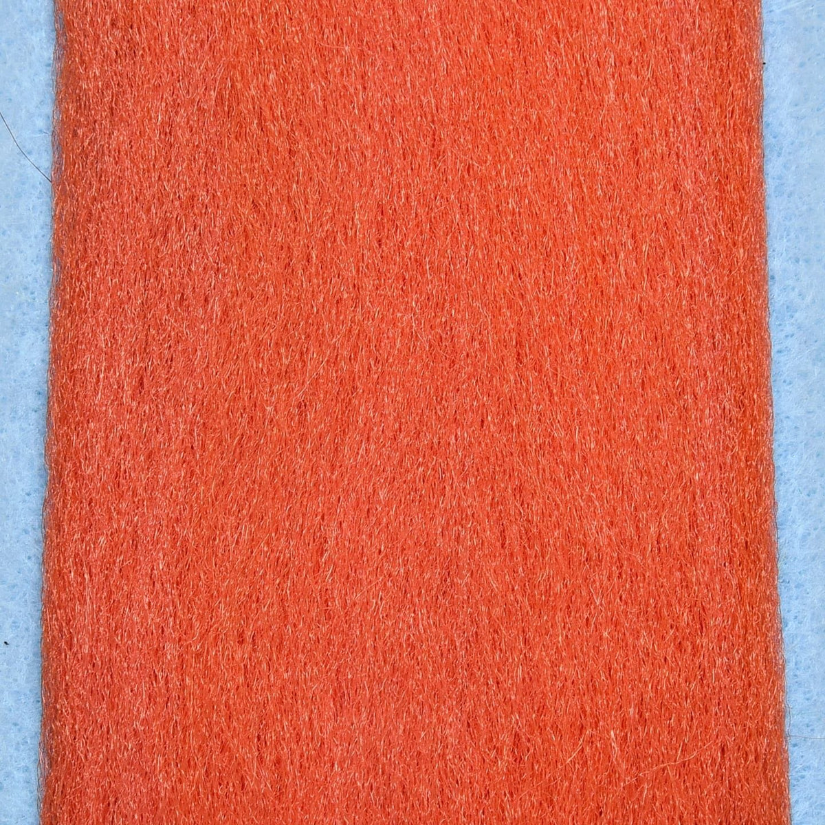 Bright orange EP Fibers synthetic strip for fly tying, dense fuzzy hair-like material on pale blue backing