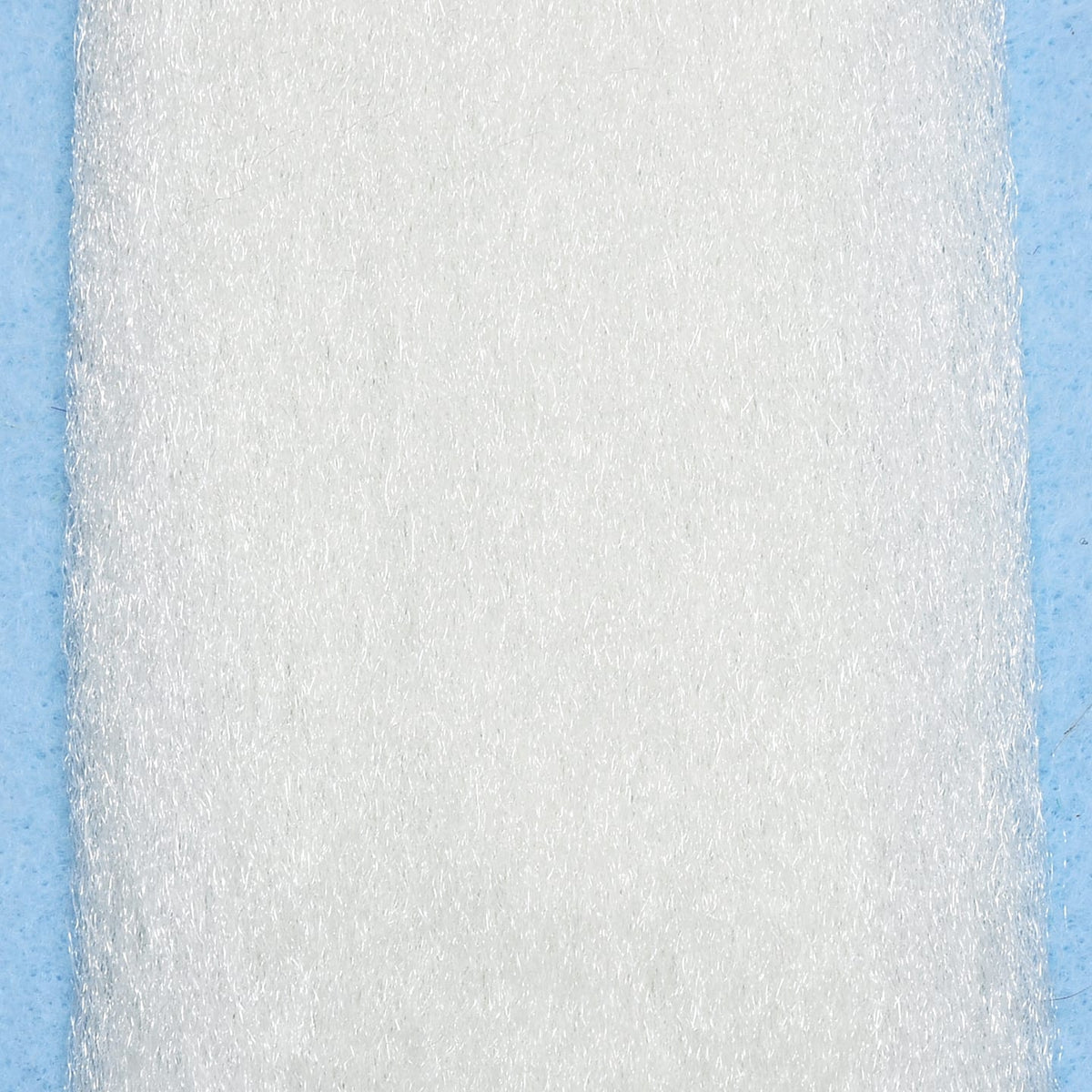 White Enrico Puglisi EP fibers pad with dense, shiny synthetic strands on pale blue background for fly tying
