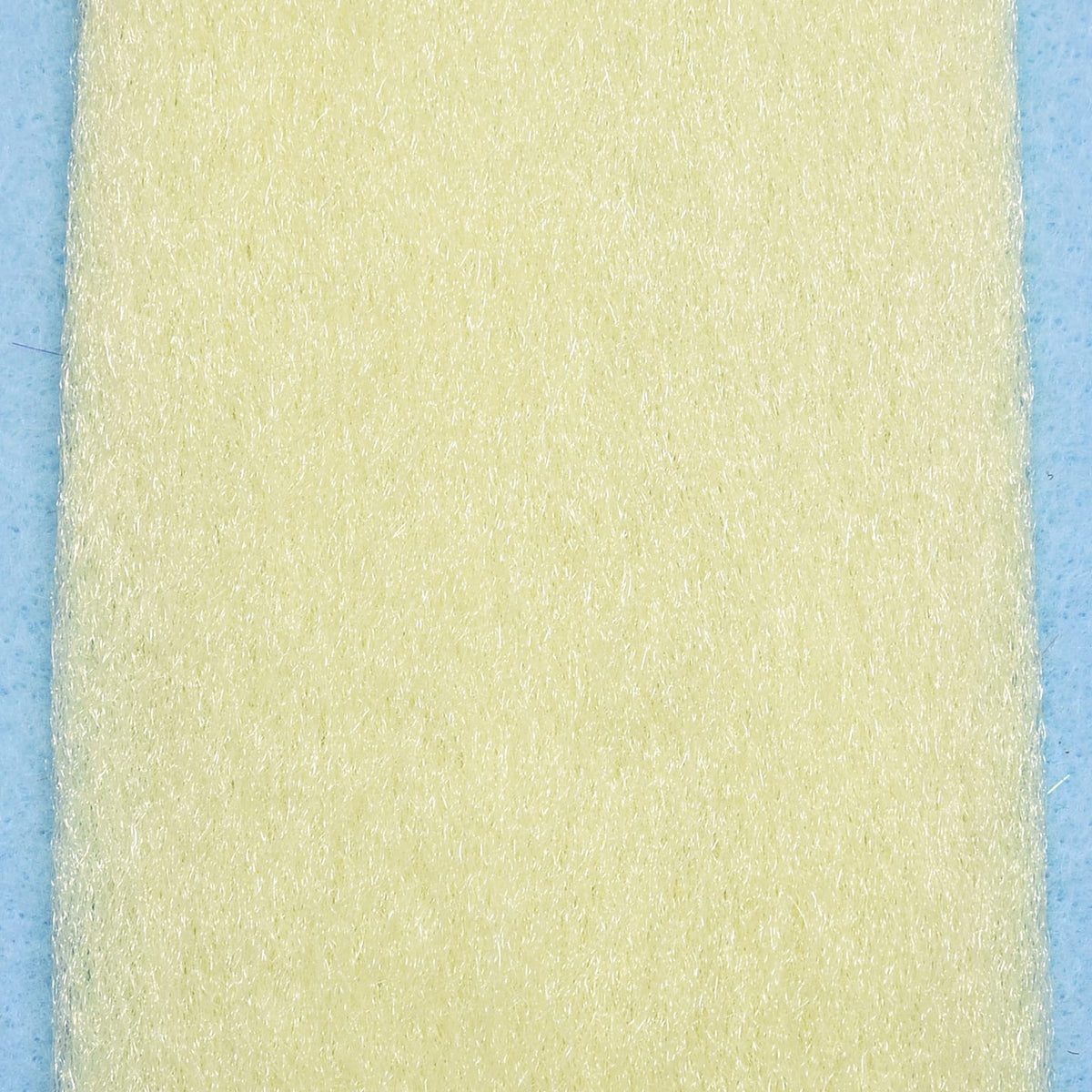 Pale cream synthetic EP Fibers sheet with fine iridescent strands for fly tying on light blue background