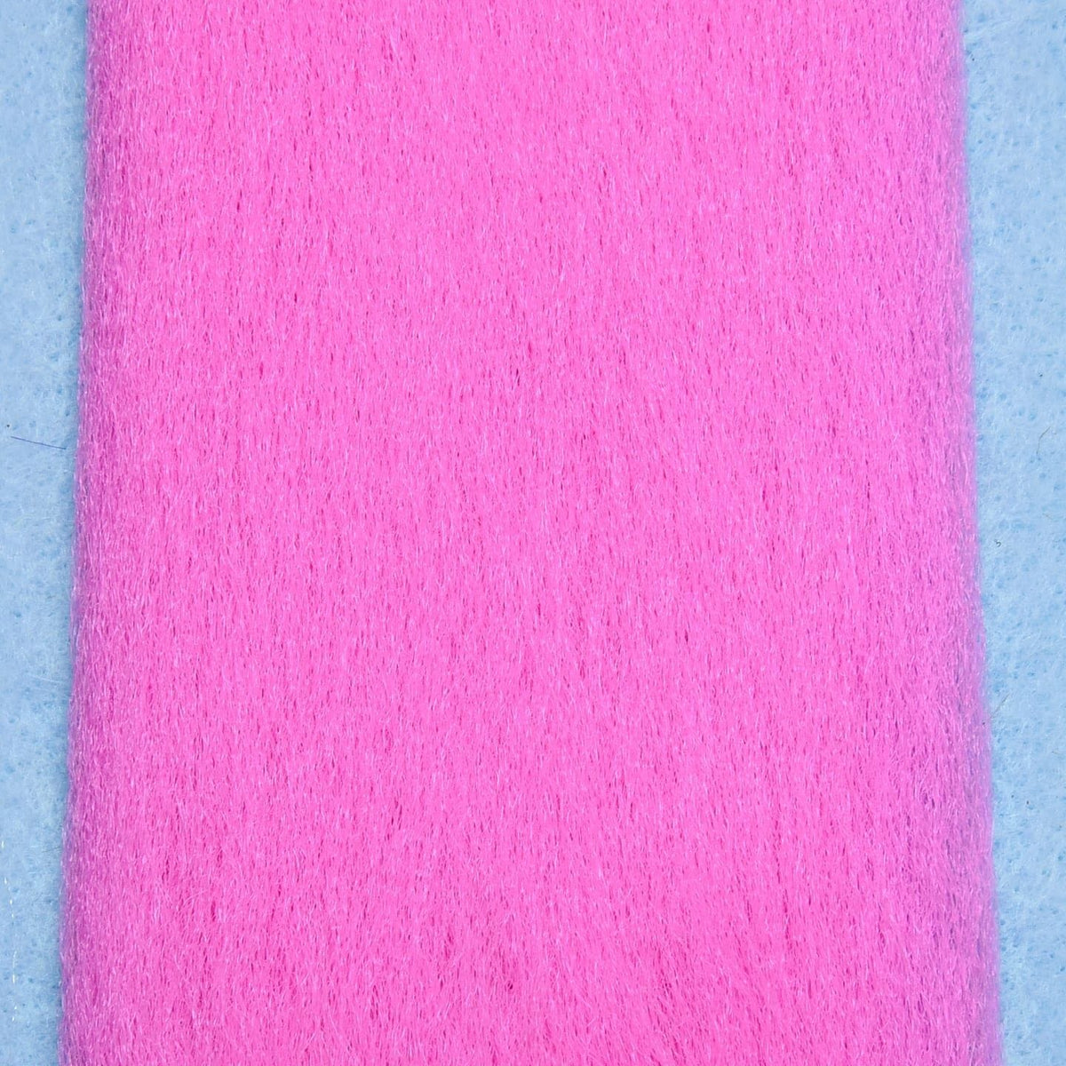 Bright pink Enrico Puglisi EP Fibers fly-tying fiber strip with fine fuzzy texture on light blue background