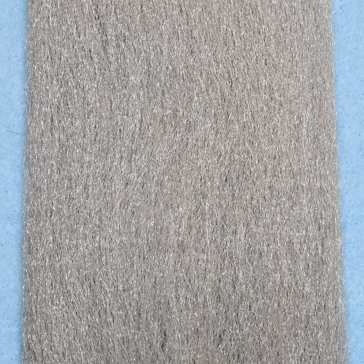 Silver-gray synthetic EP fibers with subtle metallic sheen for fly tying, long fine strands on blue backing