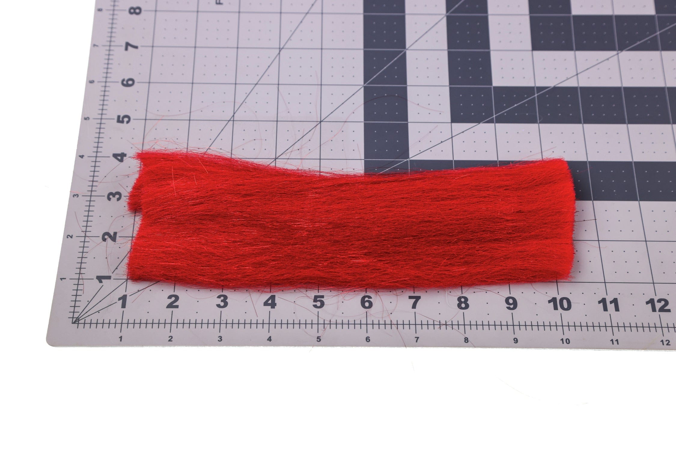 Bright red Sculpt-A-Fly synthetic fibers, hair-like fly tying fibers laid flat on gridded cutting mat