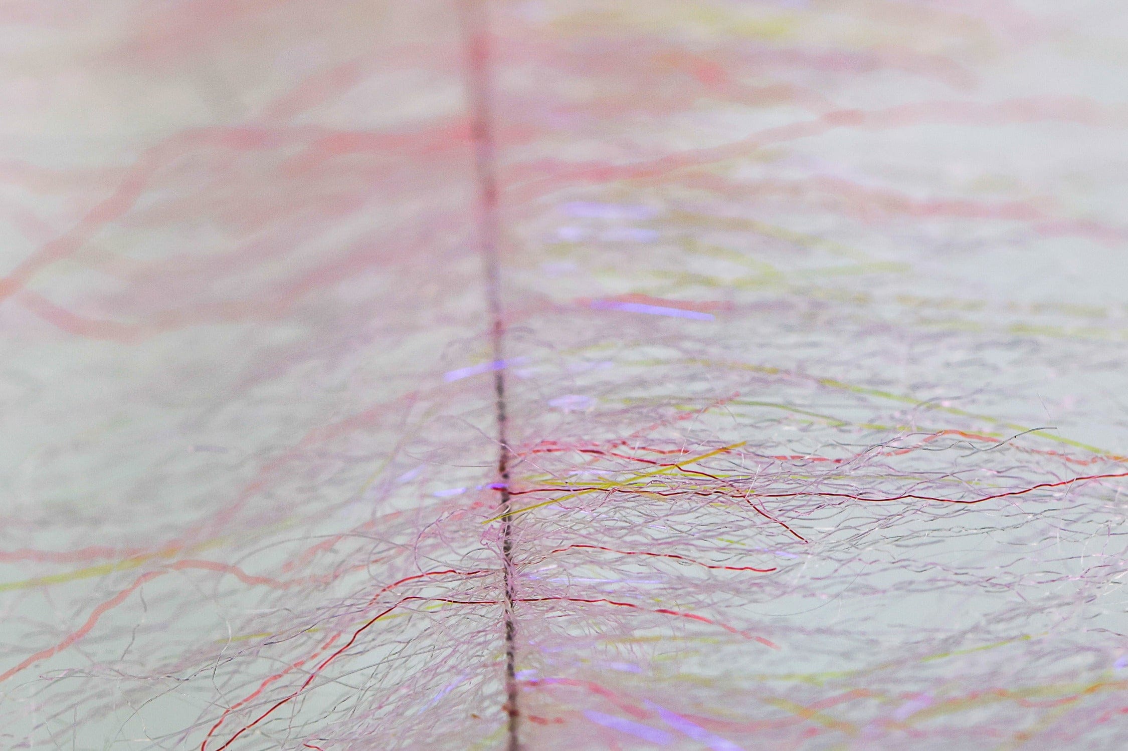 Pale pink synthetic shrimp dub brush with feathery fibers and iridescent tinsel strands for fly tying