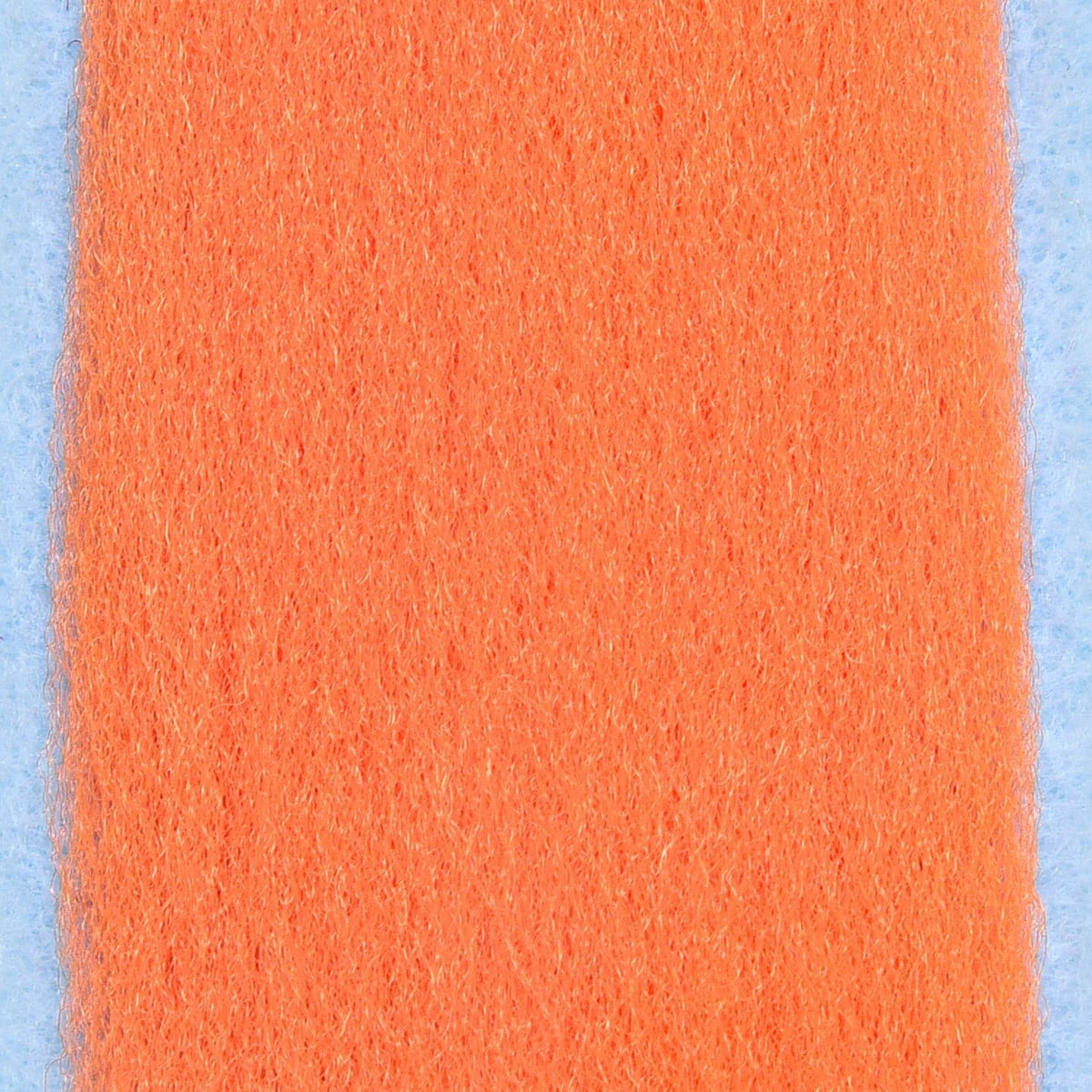 Bright orange silky synthetic fly tying fibers strip with soft fuzzy texture on light blue background