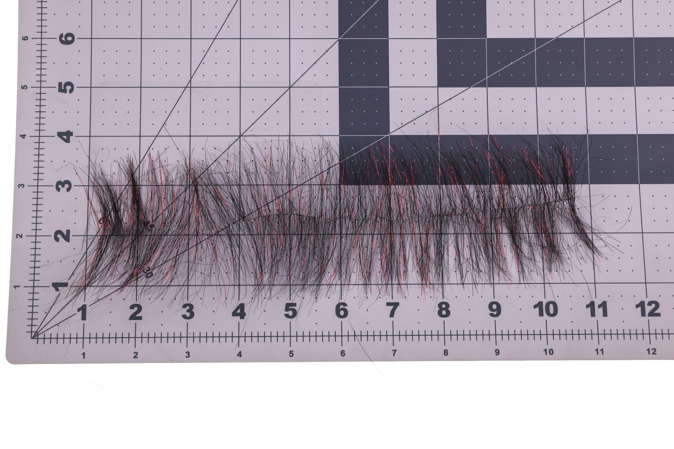 Black synthetic hair strip with red sparkle tinsel fibers, Enrico Puglisi Sparkle Brush for fly tying on measurement mat