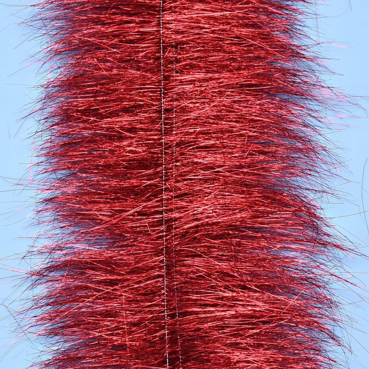 Red metallic sparkle brush with dense shimmering tinsel fibers on a central wire against pale blue background for fly tying