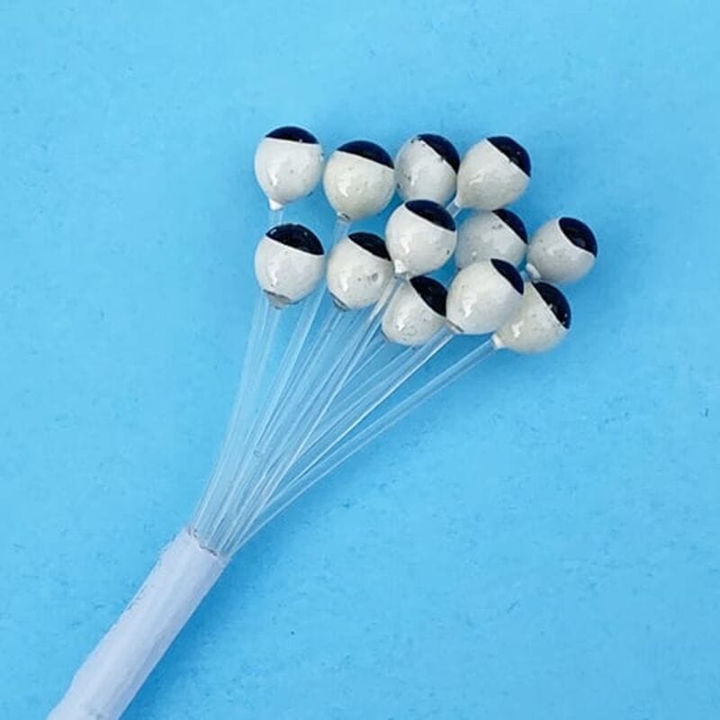 UV-X crustacean eyes for fly tying, white glossy spheres with black half-pupils on clear stems, blue background