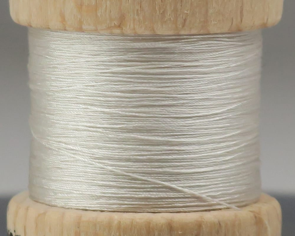 Pearl white Ephemera pure silk thread neatly wound on a natural wood spool, smooth glossy fiber for fly tying