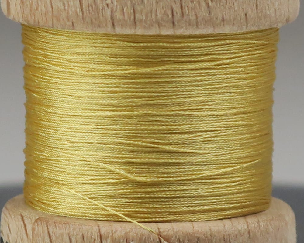 Pale gold pure silk thread wound on wooden spool, shiny smooth texture for fly tying