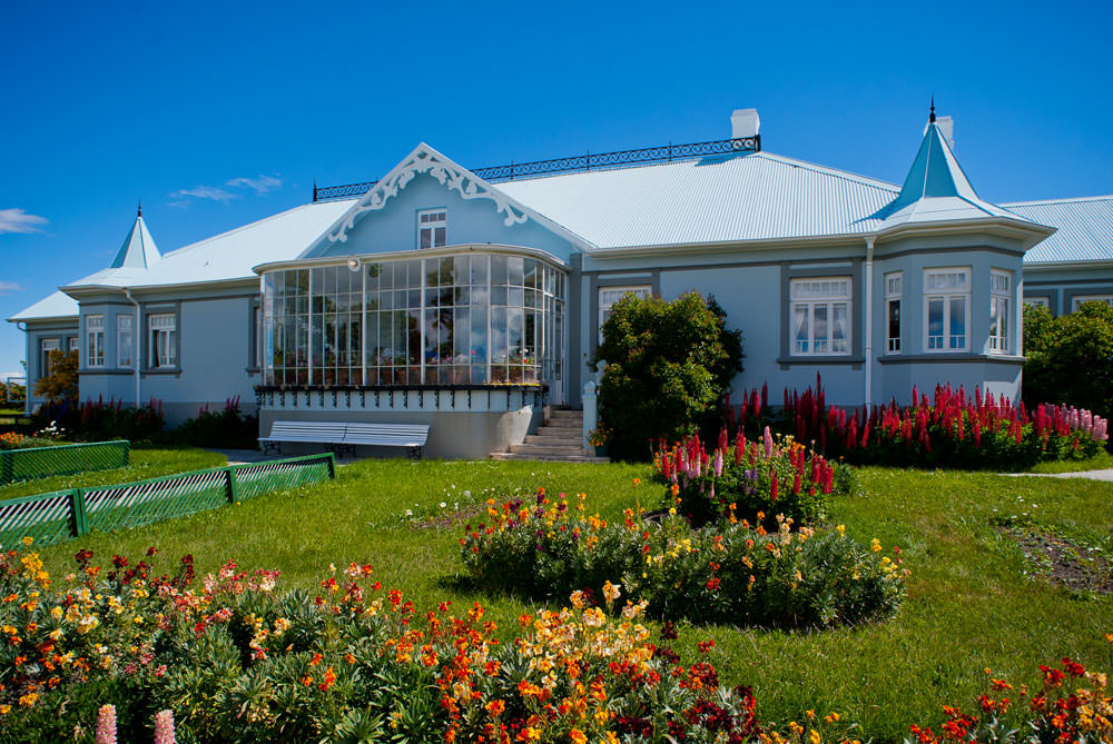La Villa de Maria Behety Lodge: elegant blue and white heritage building with turrets, surrounded by vibrant flower gardens