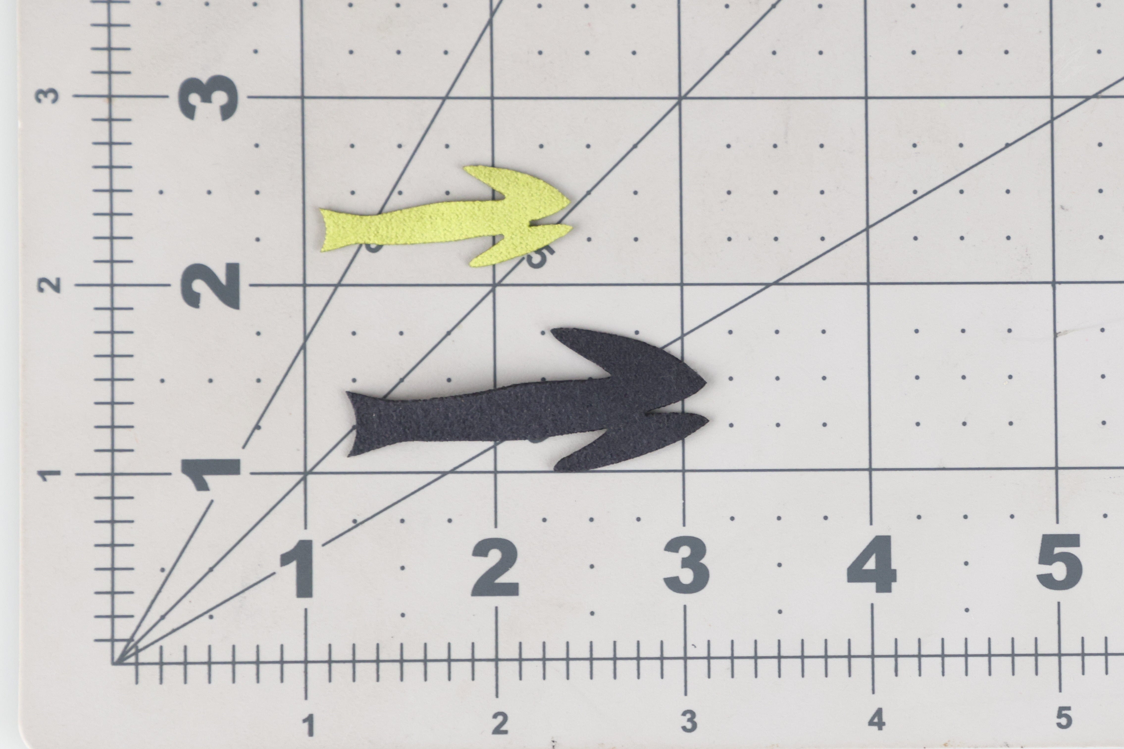 Fish-Skull Frantic Tails foam fly-tying tails: small chartreuse split tail and larger black split-tail on gridded cutting mat