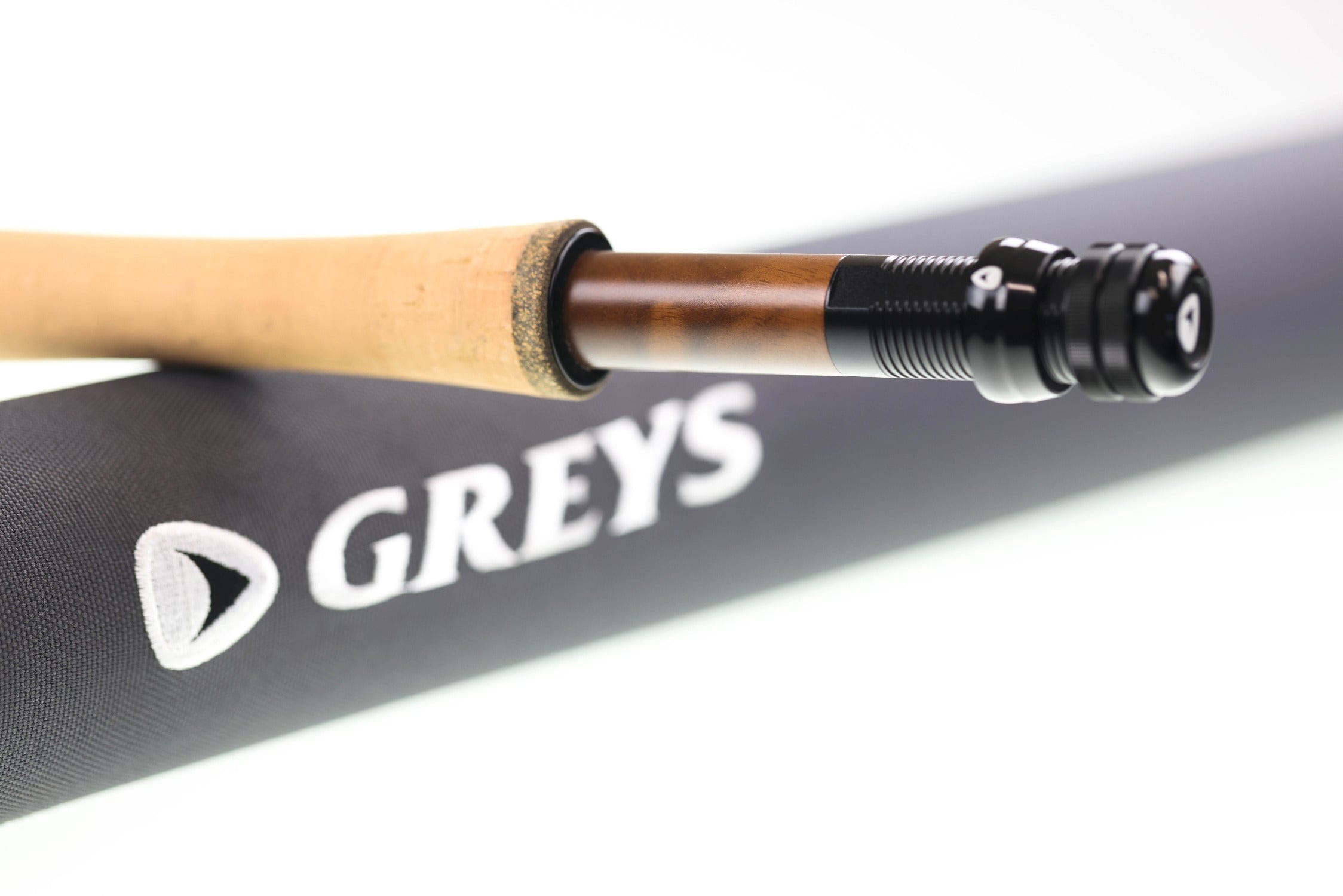 Greys Kite fly rod cork grip, varnished wood reel seat and black anodized locking rings resting on black Greys case