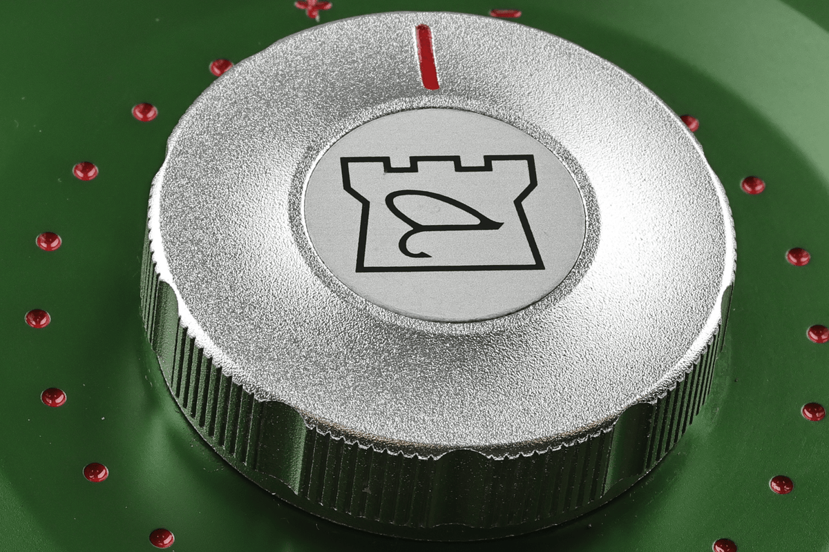 Silver textured drag knob with Hardy crest on green anodized Cascapedia MKV fly reel, knurled edge and red vent holes