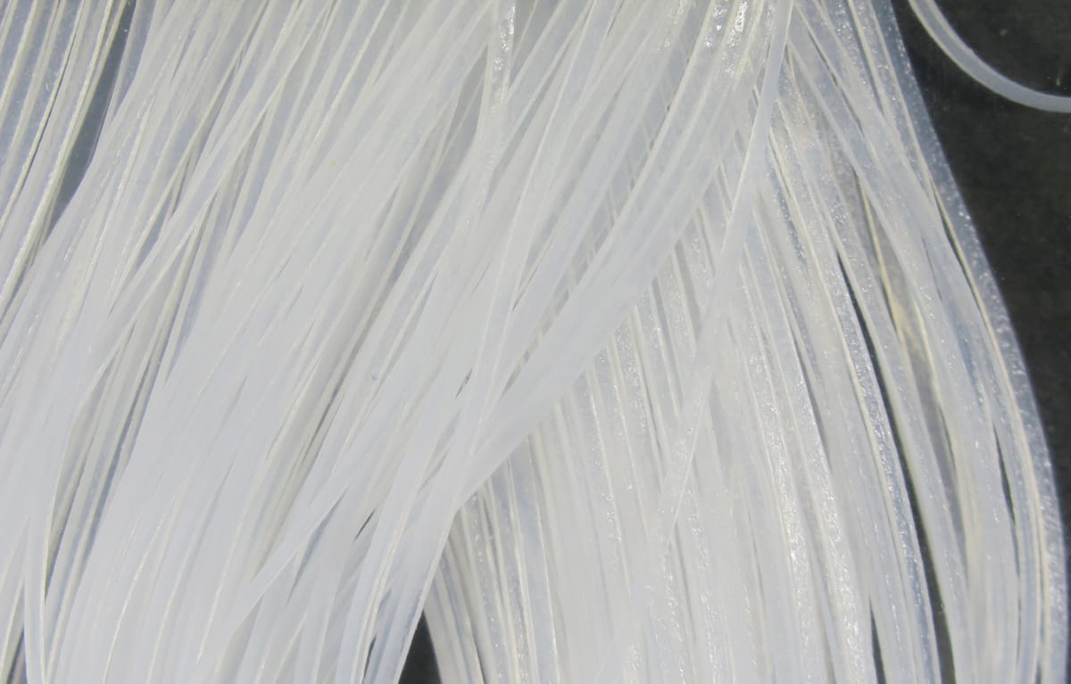 Translucent white synthetic crusher legs for fly tying, glossy flat ribbed strands