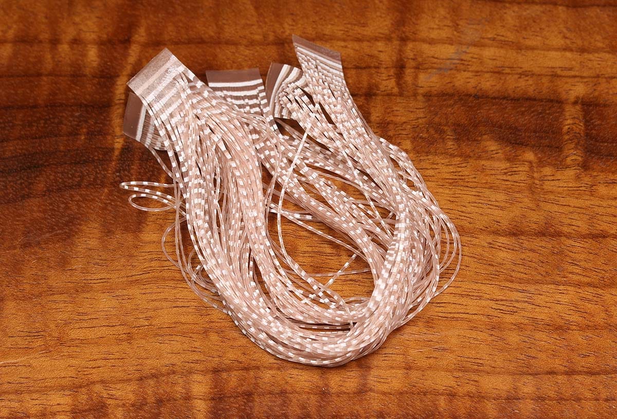 Tan and white barred silicone crusher legs bundle for fly tying, translucent flexible strands with rectangular tabs on wood