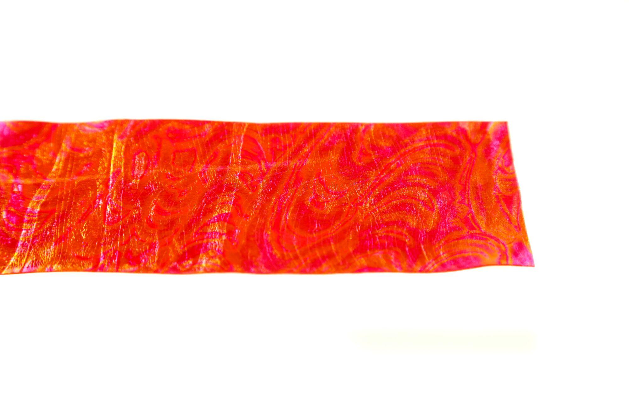 Iridescent orange-pink Chocklett's Sili Skin strip with marbled swirl texture for fly tying