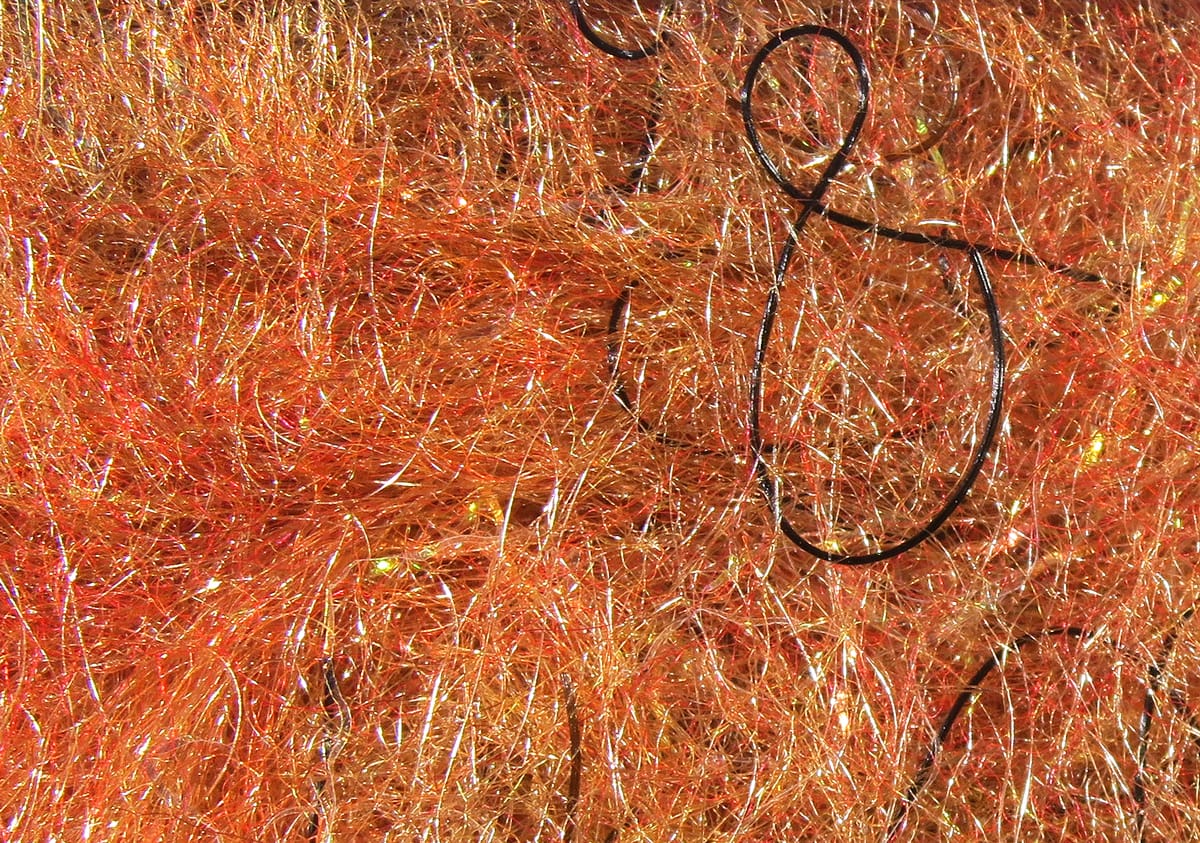 Iridescent copper-orange synthetic dubbing with gold flash and fine black looped threads for fly tying