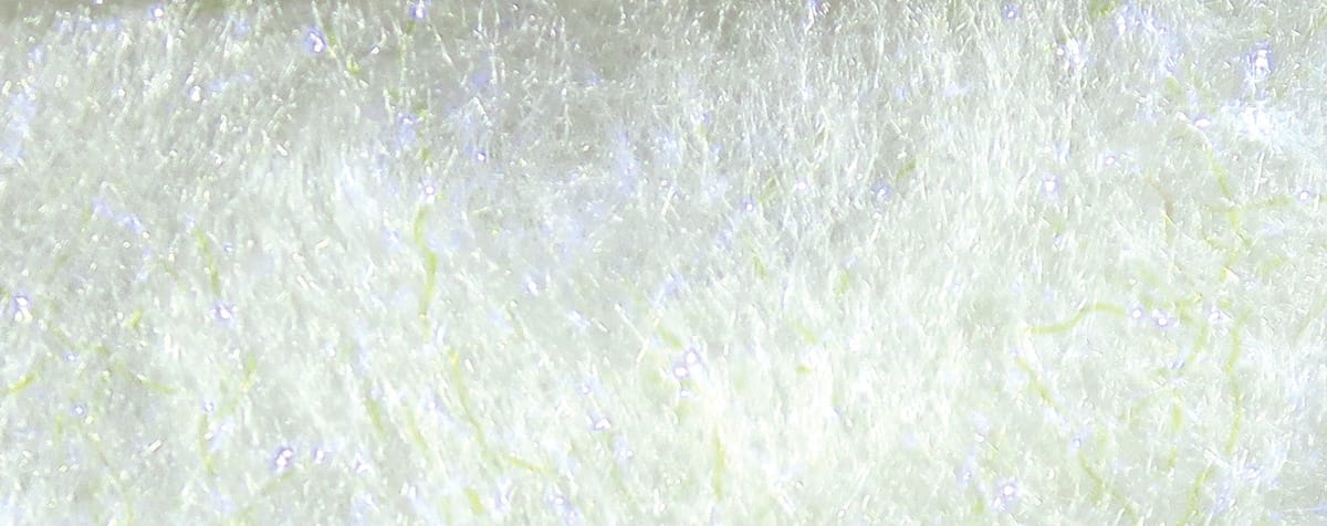 White Bruiser Blend fly tying dubbing with fluffy fibrous texture, pale yellow strands and subtle iridescent sparkle