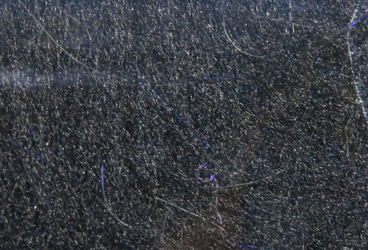 Dark charcoal synthetic dubbing with fine fuzzy fibers and subtle blue iridescent strands for fly tying