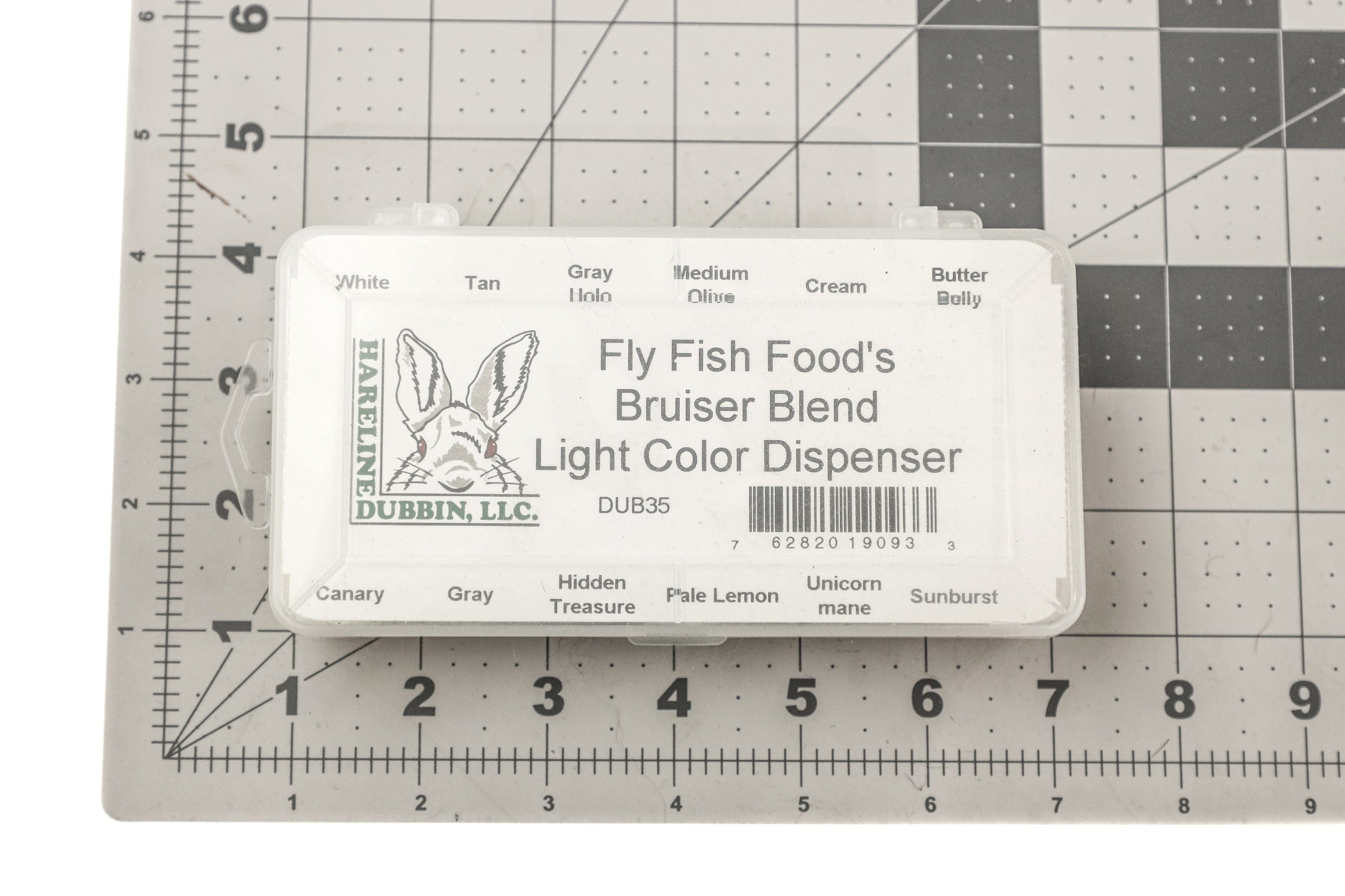 Translucent plastic Hareline Bruiser Blend Light fly tying dubbing dispenser with rabbit logo on gray grid cutting mat