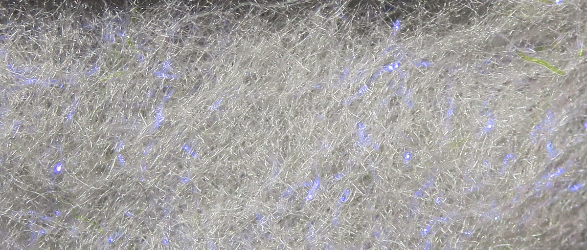 Silver-white synthetic dubbing with fine shiny fibers, blue iridescent flashes and tiny green flecks for fly tying