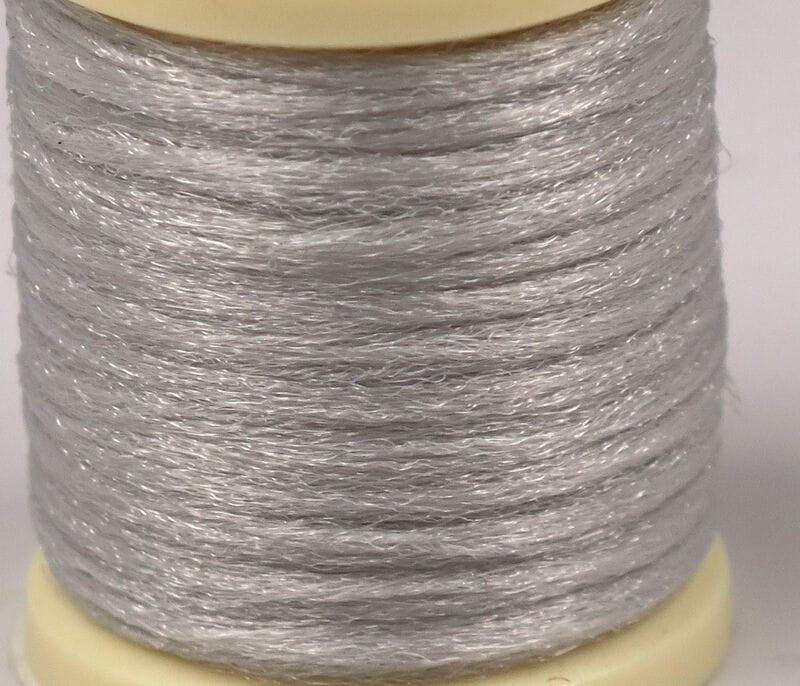 Hareline Antron yarn spool in pale silver, translucent synthetic strands with subtle sparkle, fine texture for fly tying