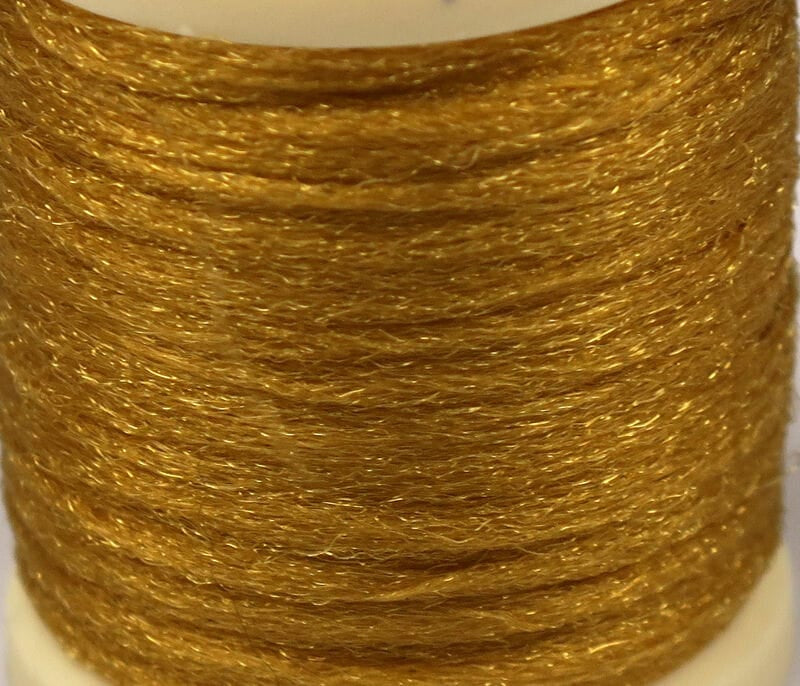 Golden Hareline Antron yarn spool with shimmering synthetic fibers for fly tying, fine textured metallic gold strands